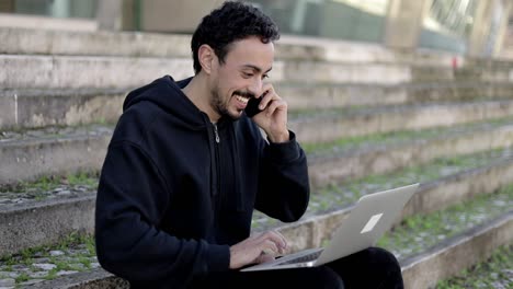 Cheerful-man-using-laptop-and-smartphone